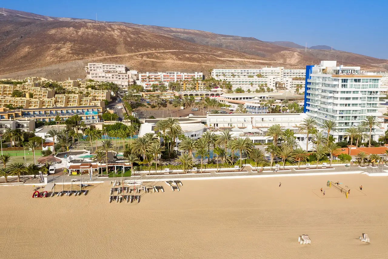 Vista aérea de la playa y el paseo de Morro Jable, con hoteles y apartamentos al pie de la montaña