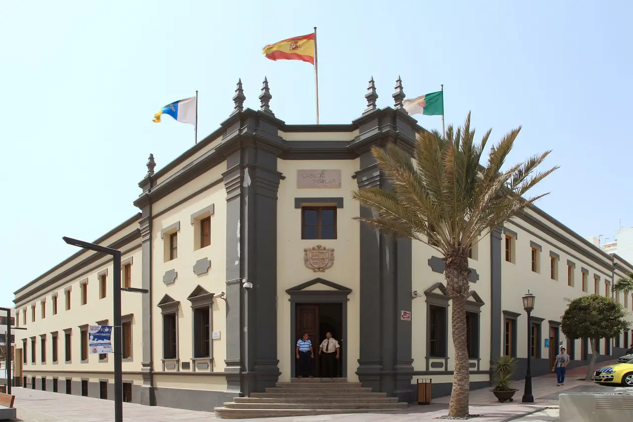 Fachada del edificio del Cabildo de Fuerteventura en Puerto del Rosario, con banderas y una palmera