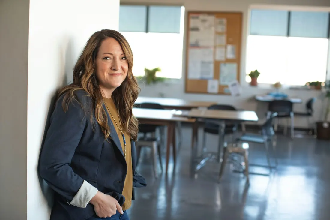 Profesora en un aula luminosa con mesas y ventanales