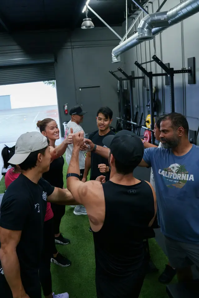 Group of gym members high-fiving after a class