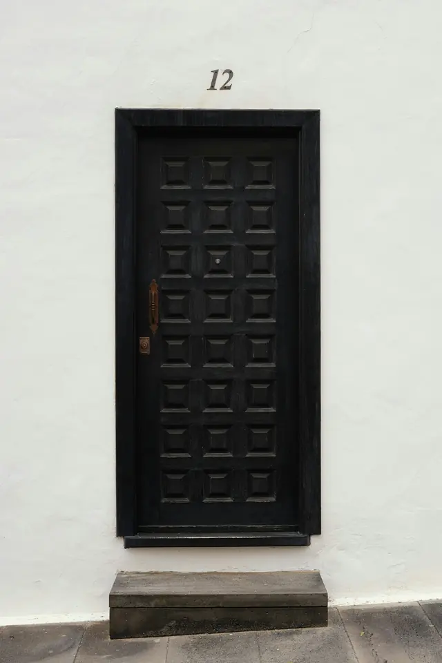 Puerta de madera oscura en una fachada encalada
